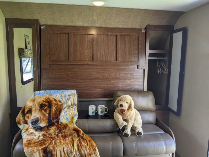 Cozy RV rental interior with a sofa, two dog plushies, and mugs, showcasing a compact and functional travel space.. Other Other 2017
