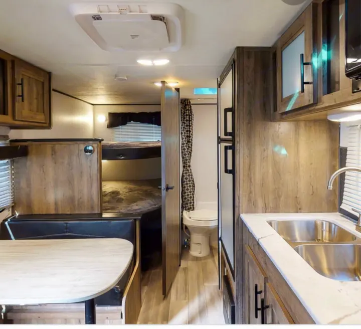 Spacious RV rental interior featuring a kitchen, dining area, bunk beds, and bathroom for comfortable travel.. Pioneer BH170 2021