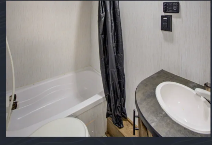 Full view of a compact RV rental bathroom featuring a tub/shower, toilet, and sink vanity.. Pioneer BH170 2021