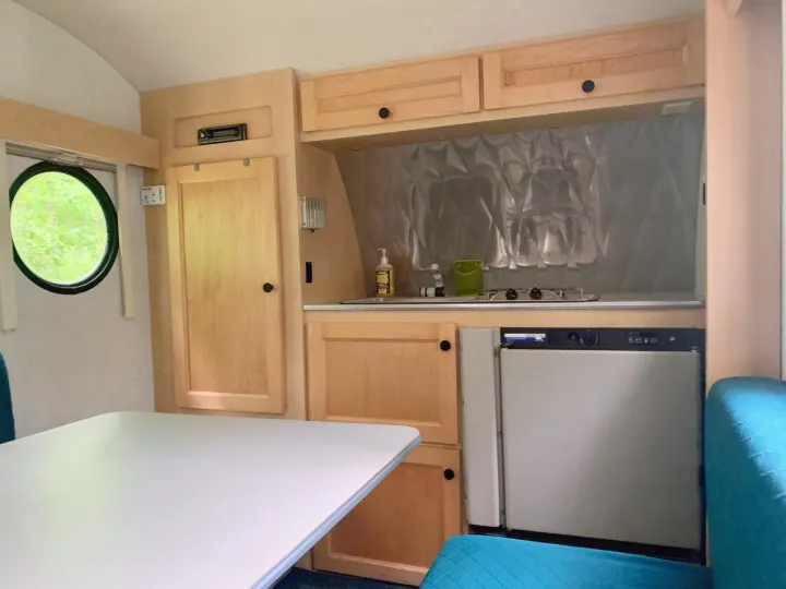 Compact RV rental interior: kitchen, dinette, and seating in a well-lit space with a circular window.. T@B T16 2008