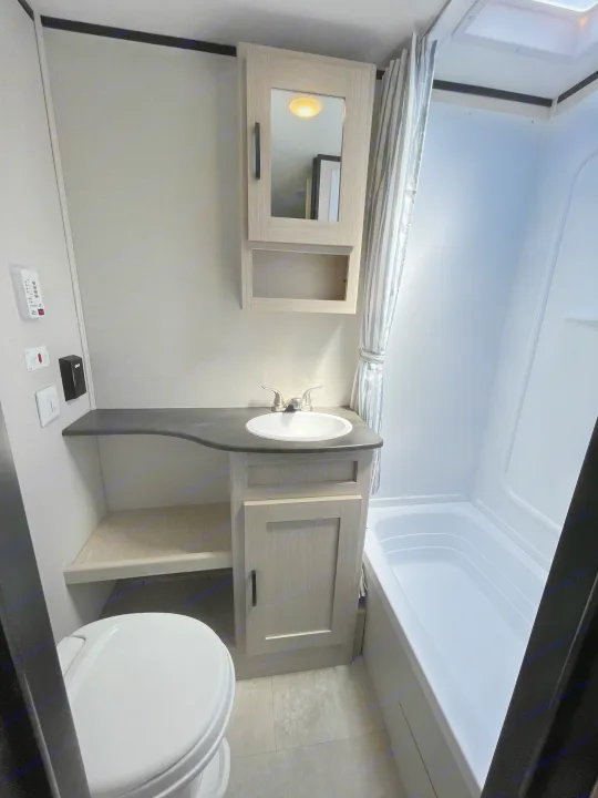 RV rental bathroom with a compact layout, featuring a toilet, vanity with sink, mirror cabinet, and tub/shower combo.. Coachmen Apex 2021
