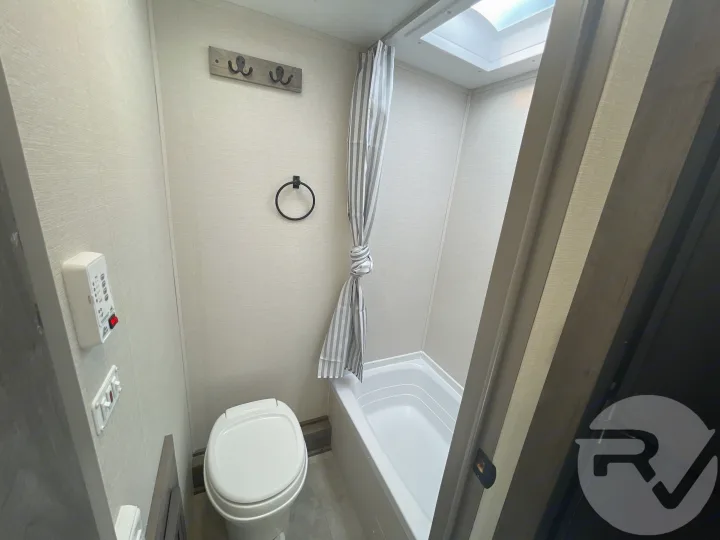 Inside an RV rental bathroom: features a compact toilet, shower/tub, and a skylight for a bright, functional space on the road.. Coachmen Apex 2021