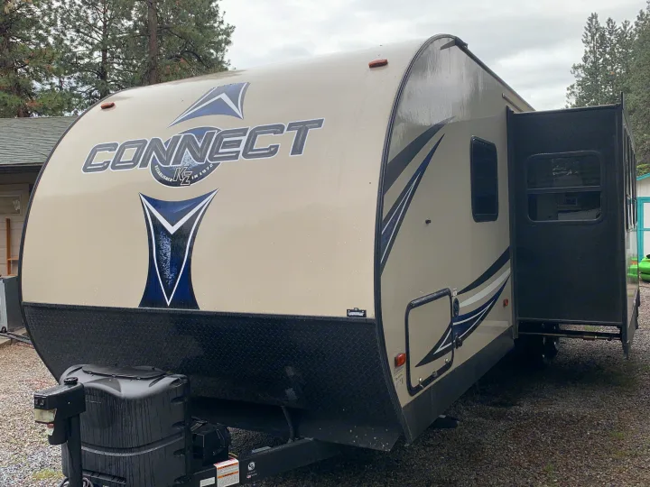 Tan KZ Connect travel trailer RV rental parked on gravel with an open door, ready for your next adventure.. K-Z Manufacturing Connect 2018
