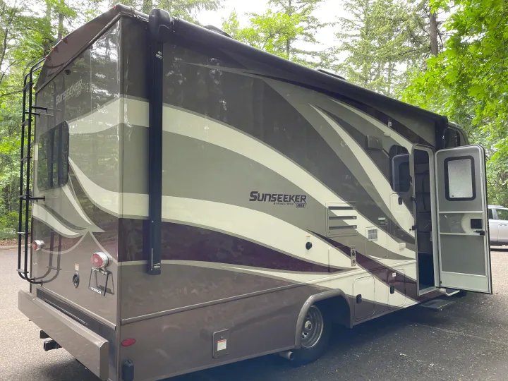 Stylish Sunseeker rv rental motorhome parked among trees with door open, ready for your next outdoor adventure.. Forest River Sunseeker 2019