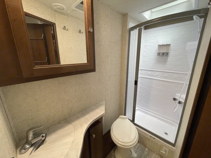 Clean, compact RV rental bathroom with vanity, toilet, and shower. Perfect for your travels.. Forest River Sunseeker 2019