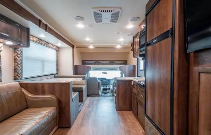 Spacious rv rental interior featuring a kitchen, dinette, and living area with wooden cabinets and comfortable seating.. Jayco Redhawk 2018