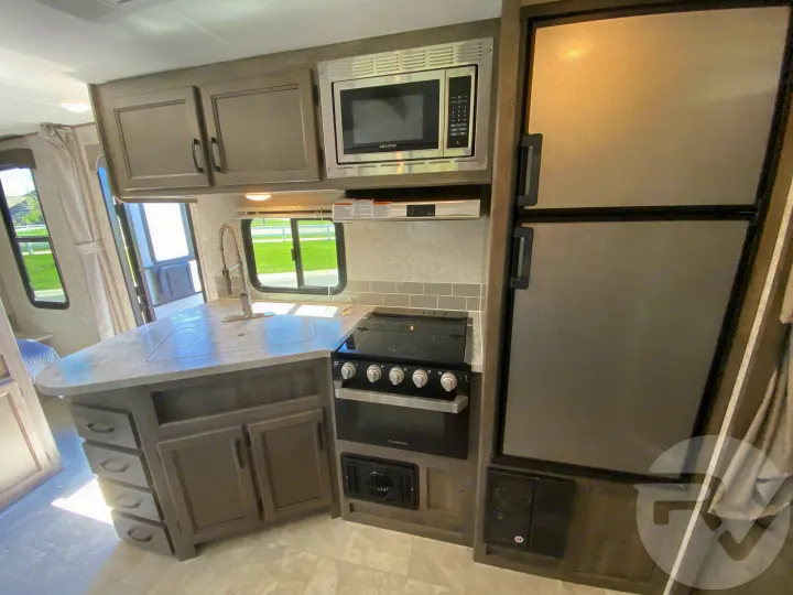 Well-equipped RV rental kitchen: sink, microwave, stove, refrigerator, and plenty of cabinet storage for your travels.. Coachmen Apex 2021