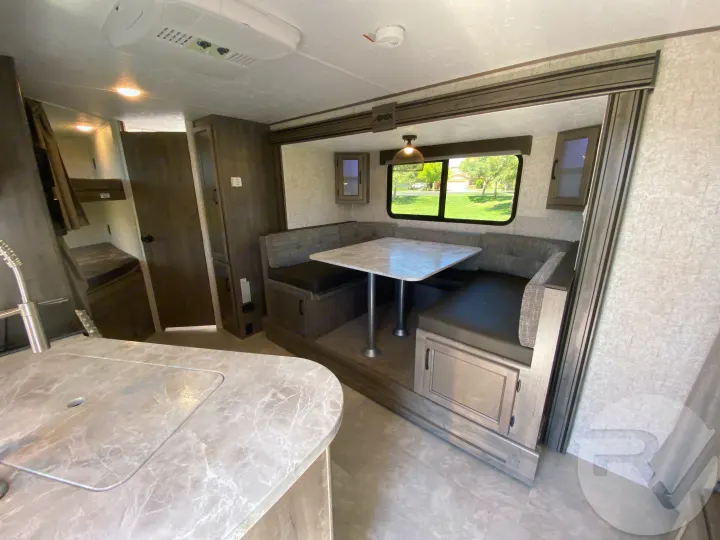 Inside a modern rv rental with a bright dinette, kitchen counter, and bunk beds. Ready for your trip!. Coachmen Apex 2021
