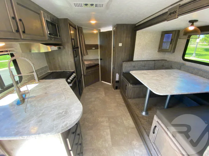 Modern RV rental interior with a full kitchen, cozy dinette, and sleeping bunks. Great for travel!. Coachmen Apex 2021