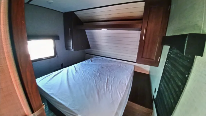 Cozy RV rental bedroom with a comfortable bed, overhead cabinets, and a side window, perfect for your next adventure.. Crossroads Zinger 2019