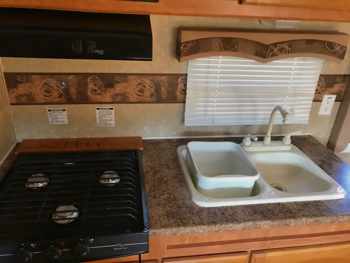 RV rental kitchen amenities: gas stovetop, sink with basin, and overhead range hood. Perfect for your next trip.. Gulf Stream Ameri-Lite 25 BS 2008
