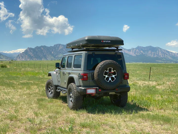 Gray Jeep Wrangler with iKamper rooftop tent, an ideal setup for an RV rental experience in the scenic mountains.. Jeep Wrangler Unlimited 2021