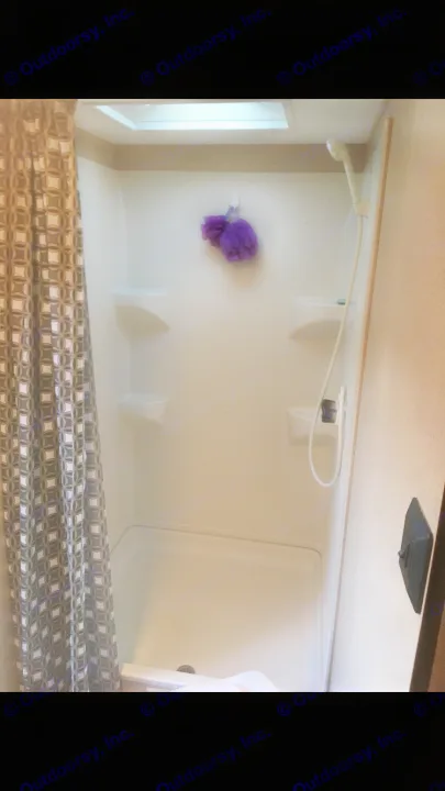Compact RV rental shower featuring a patterned curtain, multiple shelves, showerhead, and bright skylight overhead.. Jayco Jay Flight 2016