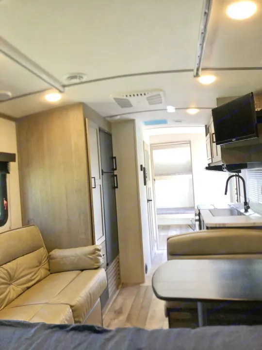 Spacious RV rental interior featuring a living area, kitchen, dining booth, and bunk beds. Ideal for family trips.. Keystone Outback Ultra-Lite 2021