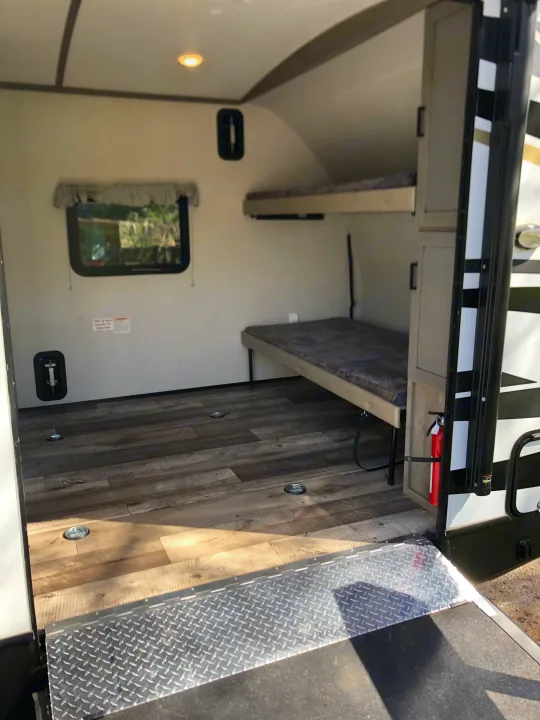 Explore this RV rental's versatile interior with bunk beds, durable wood-look flooring, and ample cargo space via a ramp.. Keystone Outback Ultra-Lite 2021