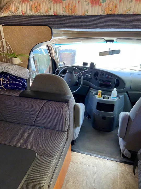 Spacious RV rental interior featuring a cozy sleeping bunk, comfortable seating, and a detailed driver's cockpit.. Thor Motor Coach Four Winds Majestic 2009