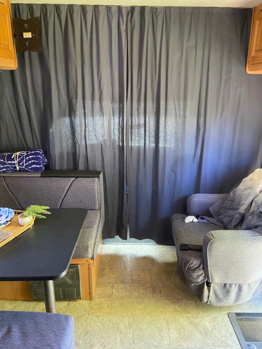 Cozy RV rental interior featuring a dinette, armchair, and dark curtains. Ideal mobile living space.. Thor Motor Coach Four Winds Majestic 2009