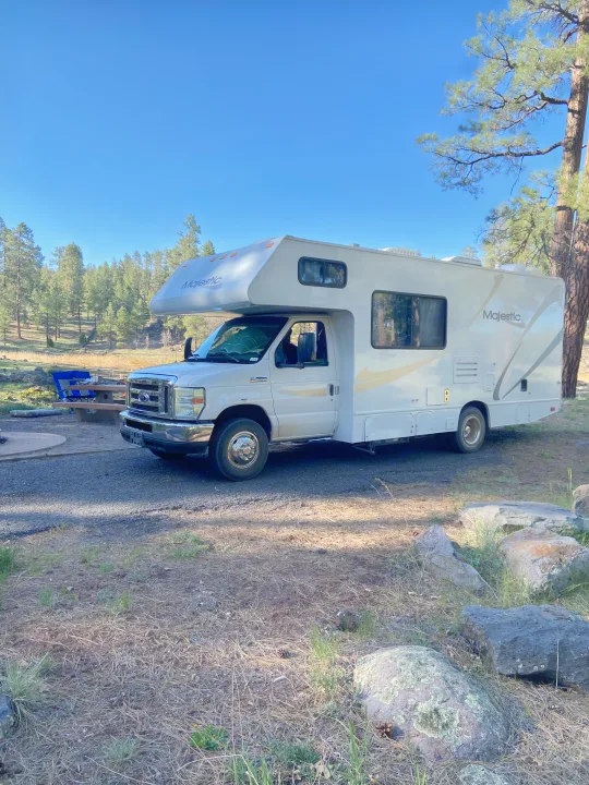 Majestic RV rental parked at a tranquil forest campsite on a sunny day.. Thor Motor Coach Four Winds Majestic 2009