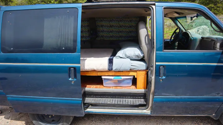 Side view of a blue camper van with open door revealing a bed, storage, and curtains. Great for an RV rental.. Chevrolet Other 2003