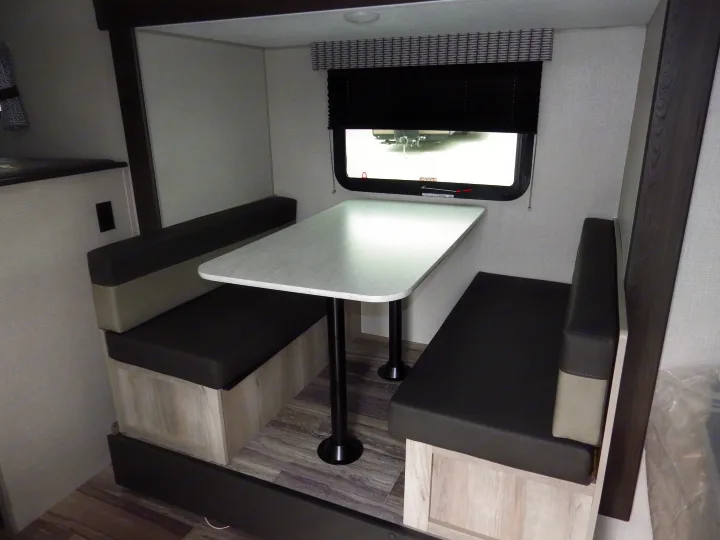 Functional RV rental dinette featuring a table and opposing benches, ideal for dining or work in a compact space.. KZ 181BH 2021