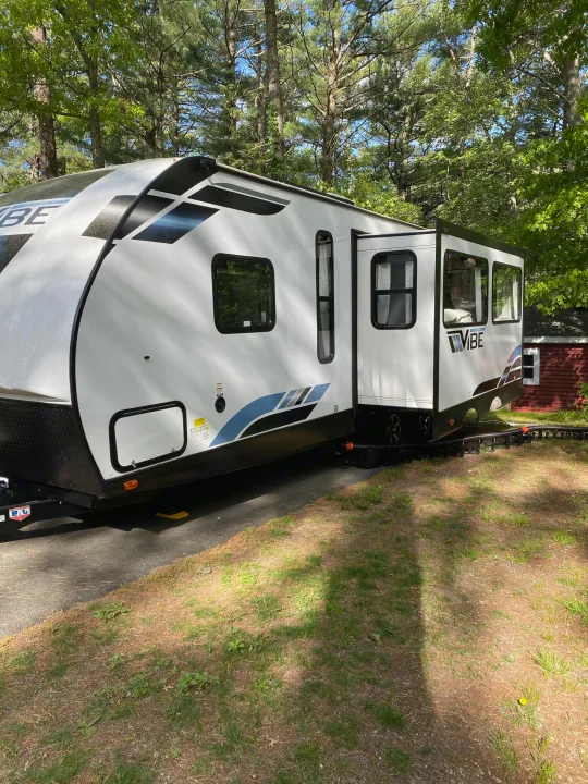 Relax in nature with this VIBE rv rental travel trailer, featuring an extended slide-out at a scenic campsite.. Forest River Vibe 2021