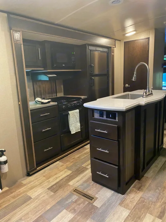A full kitchen inside an rv rental, showcasing dark cabinetry, light counters, appliances, and island.. Other Fun Finder 2017
