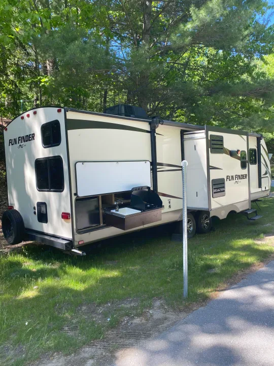 Fun Finder travel trailer RV rental parked at a shady campsite, showcasing its outdoor kitchen and extended slide-out.. Other Fun Finder 2017