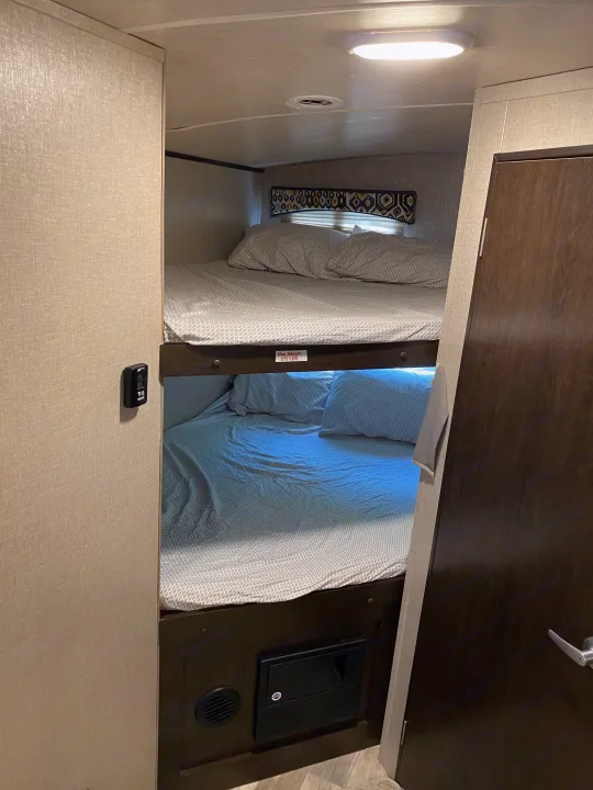 Cozy twin bunk beds inside an RV rental, with light bedding. A 275 lbs weight limit sign and wall controls are visible.. Other Fun Finder 2017