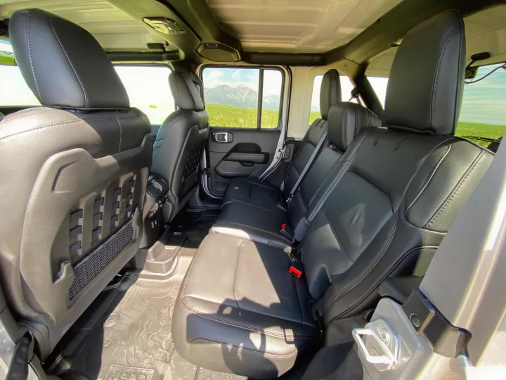 Rear passenger area of a rugged SUV with black seats & scenic views, perfect for an RV rental journey.. Jeep Wrangler Unlimited Rubicon 392 2021