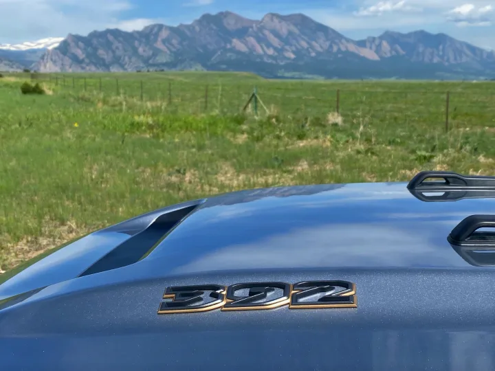 Scenic mountain view from an RV rental, showing its hood with a '392' emblem & roof rails over green fields.. Jeep Wrangler Unlimited Rubicon 392 2021