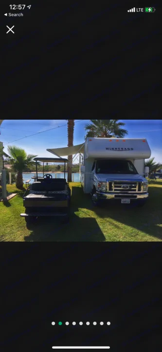 Winnebago RV rental with golf cart parked on grass by water and palm trees, perfect for outdoor leisure.. Winnebago Minnie Winnie 2015