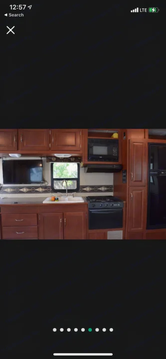 RV rental kitchen interior with wood cabinets, sink, stove, microwave, TV, and refrigerator. A compact, functional space.. Winnebago Minnie Winnie 2015