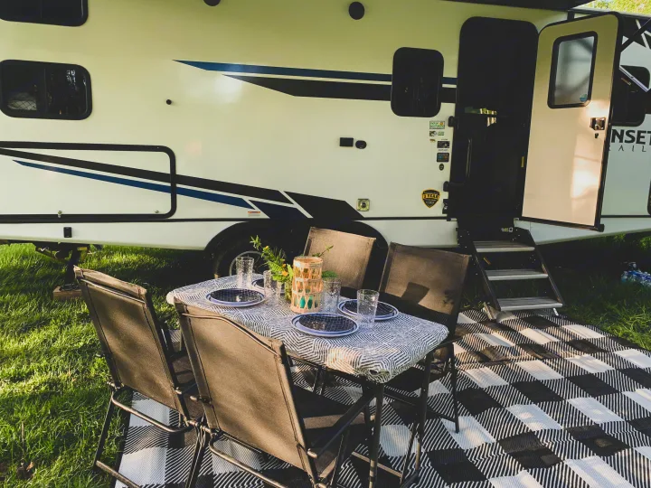 An RV rental provides a cozy outdoor dining spot with a set table, chairs, and stylish checkered mat for camping.. Crossroads RV Sunset Trail Super Lite 2021