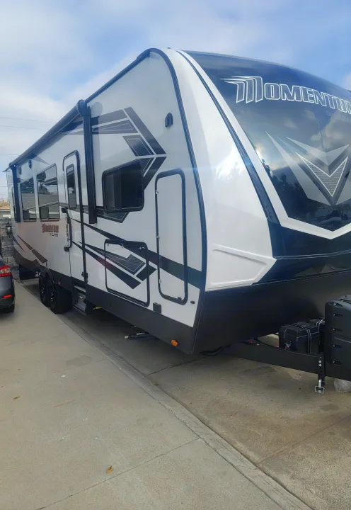 Full view of a modern white and black Momentum G-Class travel trailer, ready for your next RV rental adventure.. Grand Design Momentum 2021