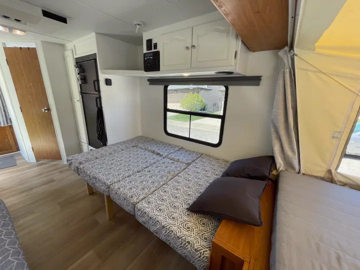 RV rental: Pop-up camper interior with beds, cabinets, fridge, and window looking out to a neighborhood street.. Forest River Rockwood Roo 2010