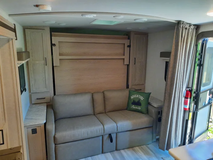 Cozy RV rental interior featuring a versatile sofa, murphy bed, and ample storage for travel.. Forest River Rockwood Mini Lite 2021