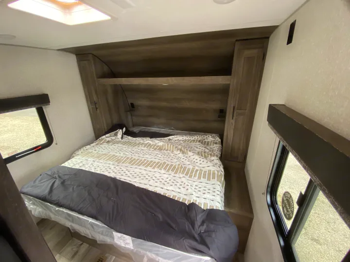 Spacious RV rental bedroom featuring a queen bed with new mattress, built-in storage, and side windows.. Sportsmen LE 2021