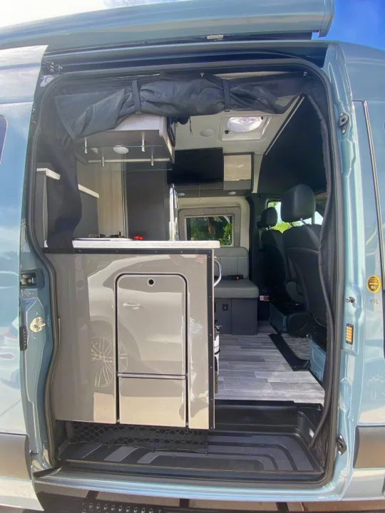 View looking in from the large side door. Outdoor folding table,  bench seat with table, sink and stove.. Thor Motor Coach Other 2022