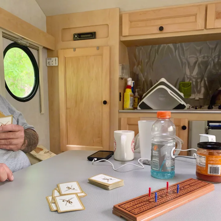 Inside an RV rental, people are enjoying a game of cribbage at a table, with drinks and a phone nearby.. T@B T16 2008