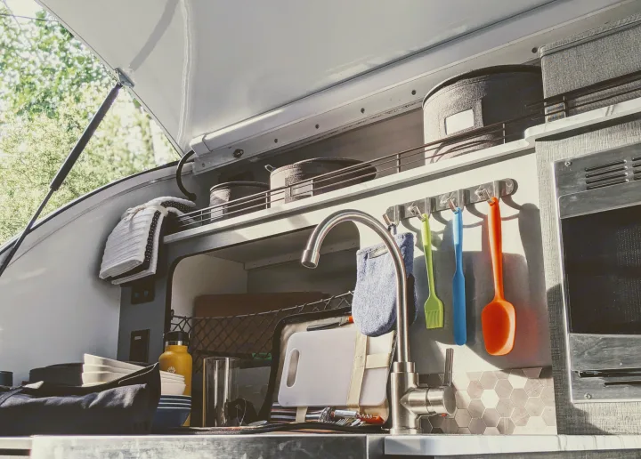 Well-equipped RV rental outdoor kitchen: sink, colorful utensils, storage, and microwave. Great for glamping!. InTech RV InTech RV Trailer 2021