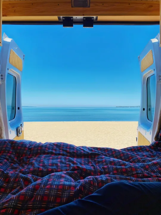 RV rental: View from inside, legs under plaid blanket, open van doors reveal beach & ocean.. RAM Promaster 1500 2017