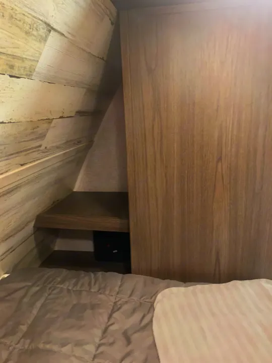 Tucked in beside the queen bed is a convenient nightstand storage spot with a charging port.. Dutchmen Kodiak 2021