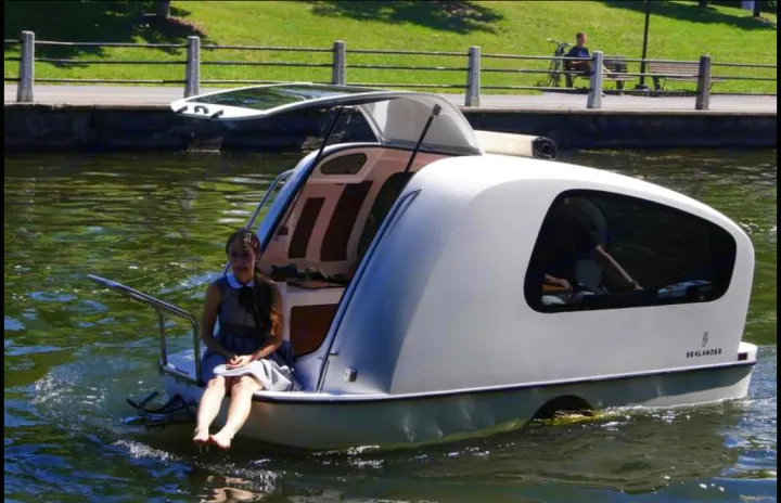 Sealander amphibious RV rental: This unique white recreational vehicle travels on land & water. A woman enjoys the stern.. Sealander Sealander 2021