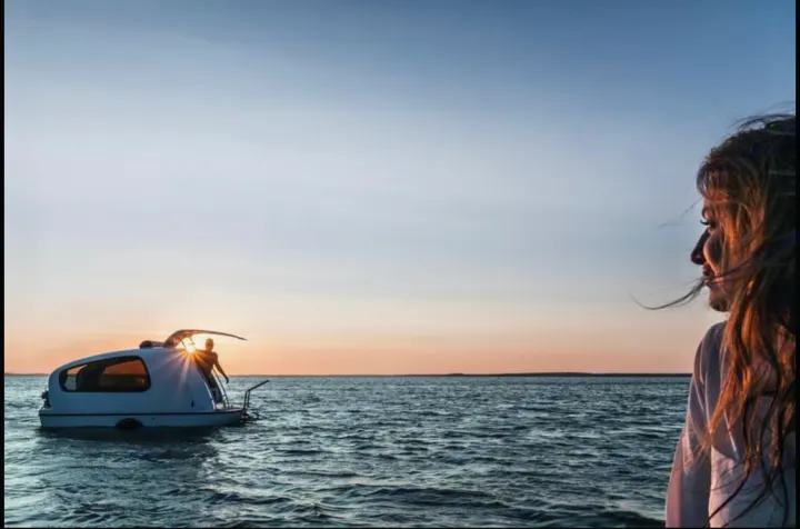 Modern floating RV/camper at sunset; person on boat, woman watching. A unique 'RV rental' for water adventures.. Sealander Sealander 2021