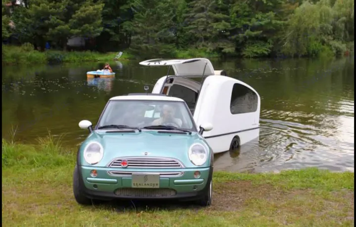 A light green Mini Cooper backs a Sealander amphibious RV into a lake. An exciting rv rental option!. Sealander Sealander 2021