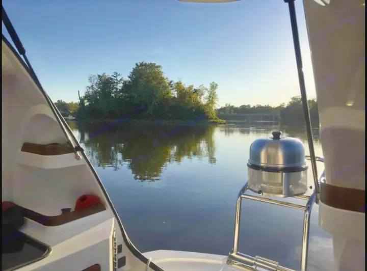 Relaxing boat view: calm river, treed island, and a grill onboard. Perfect escape, like an RV rental adventure.. Sealander Sealander 2021