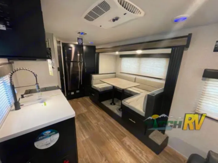 RV rental interior featuring a modern kitchen, large refrigerator, and a spacious dinette seating area. Ready for trips!. Forest River Cherokee Wolf Pup 16PFBL 2021