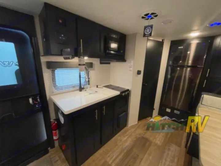 Inside this RV rental: sleek kitchen with dark cabinets, a sink, microwave, and refrigerator. Ready for adventure!. Forest River Cherokee Wolf Pup 16PFBL 2021