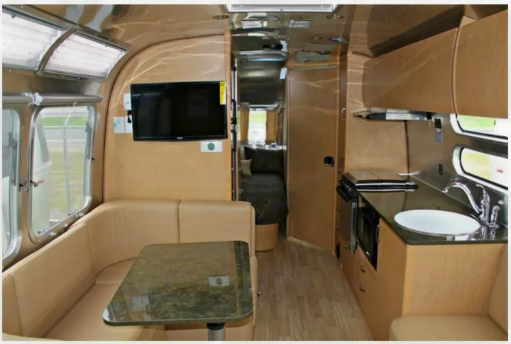 Step inside this stylish RV rental, showcasing a comfortable living area, fully equipped kitchen, and cozy bedroom space.. Airstream Flying Cloud 2016