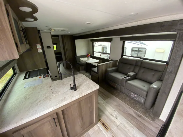Spacious RV rental interior: modern kitchen, dining booth, and comfortable reclining theater seating. Ideal for travel.. Sportsmen LE 2021